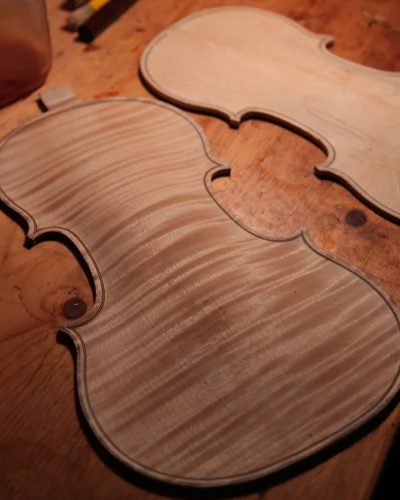 Tapa y fondo de un violín sin barnizar, todavía en blanco, apoyados sobre el banco de trabajo