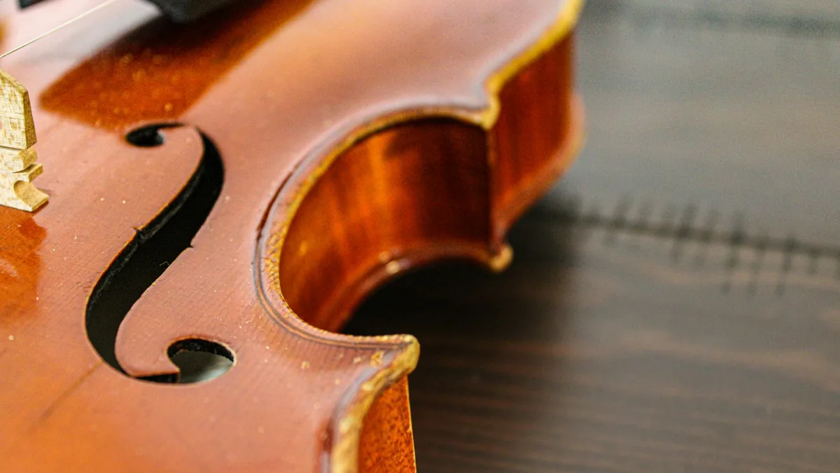 Detalle del efe y del borde de la tapa de un violín barnizado sobre una mesa de madera oscura
